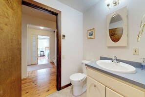 A bathroom with a white sink, a mirror, and a toilet. - Home With Deck, Great Location in the Heart of Acadia National Park (Mount Desert)