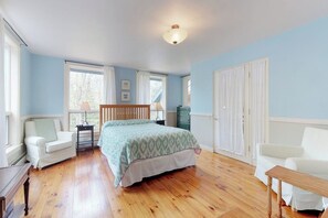 A bedroom with a bed, two chairs, a dresser, and a window with curtains. - Home With Deck, Great Location in the Heart of Acadia National Park (Mount Desert)