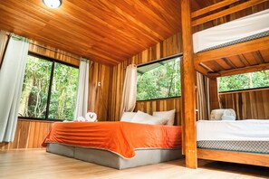Une cabane en bois avec un lit superposé, de grandes fenêtres et une vue sur la forêt.
