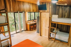 L'intérieur d'une cabane en bois, avec des lits superposés, un bureau et un téléviseur.