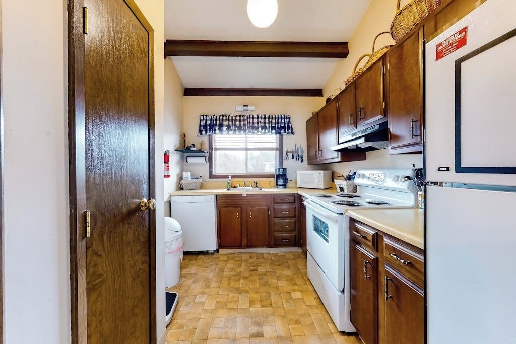 A compact kitchen with wooden cabinets, a white stove, and a microwave.