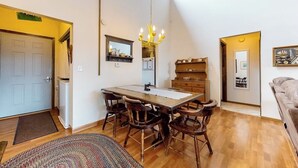 Un coin repas avec une table et des chaises en bois, un lustre et un miroir au-dessus de la table.