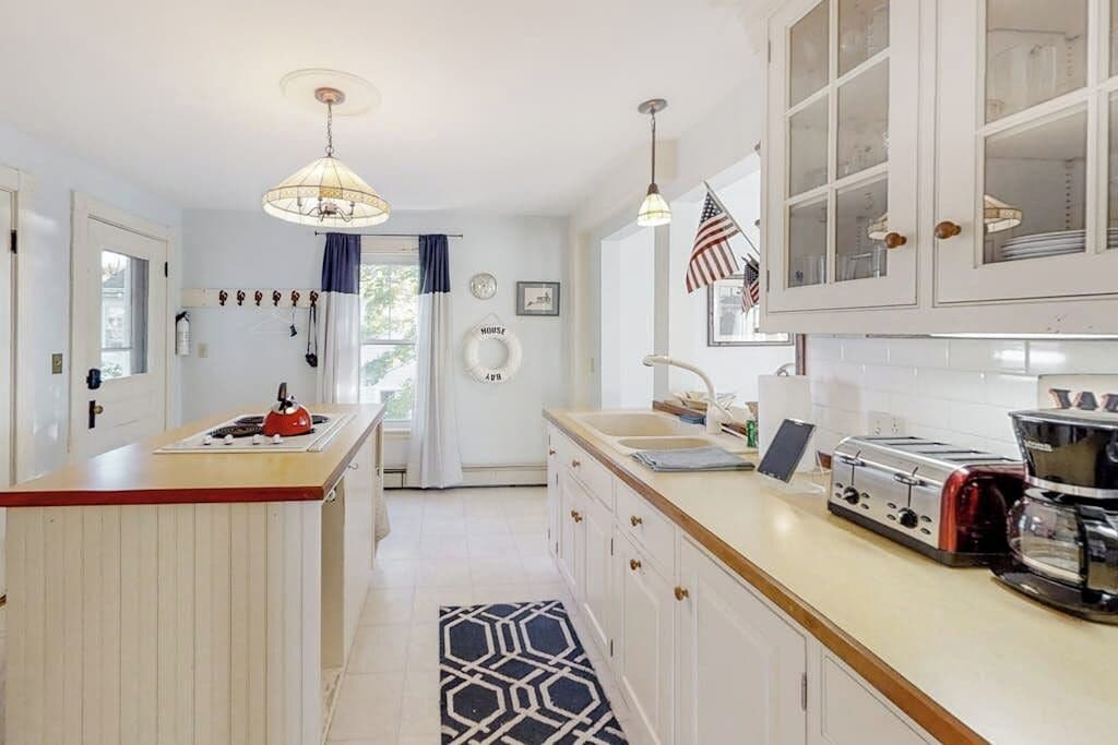 A kitchen with a central island, a stove, a toaster, and a coffee maker.