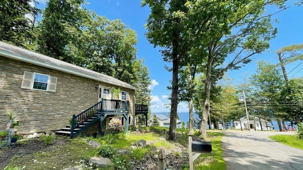 A stone building with a staircase, a porch, and a view of the water. - Slice of Heaven, Steps to the Beach (Lincolnville)