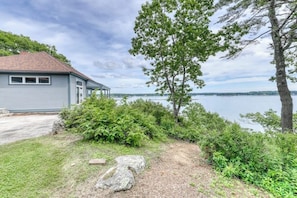 Ein Haus mit Seeblick, umgeben von viel Grün und blauem Himmel.