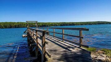 A wooden pier extending into a lake with a clear sky.