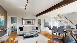 A spacious living area with a sofa, coffee table, and dining table. - Charming, Historic Cottage With Modern Upgrades - Stroll to Dining & Attractions (Boothbay Harbor)