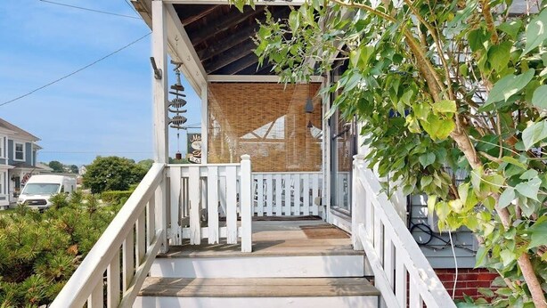 A wooden staircase with white railings leading to a covered porch. - Charming, Historic Cottage With Modern Upgrades - Stroll to Dining & Attractions (Boothbay Harbor)
