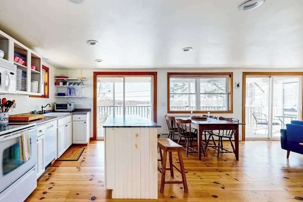 A kitchen with white cabinets, a microwave, and a dining area with a table and chairs.