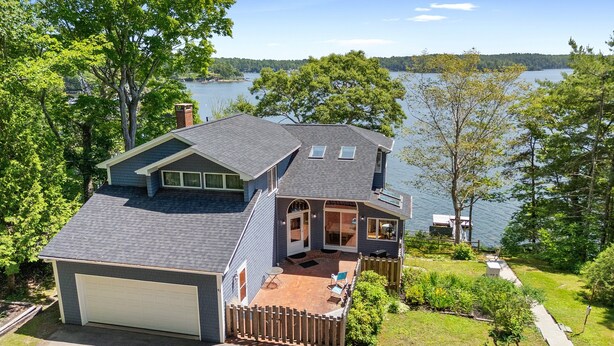 A two-story house with a garage, a deck, and a view of a lake. - Serene Waterfront Home w/ a Dock, Large Deck & Amazing Views! (Harpswell)