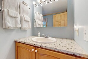 Un baño con lavabo, espejo, toallas y armarios de madera.