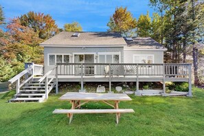 Una casa con terraza techada, un banco de madera y una escalera que sube a la terraza.