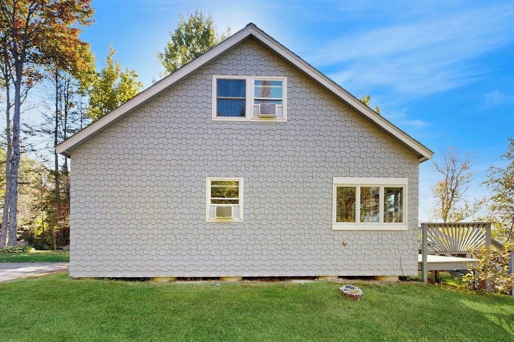 Une maison de plain-pied avec un toit à pignon, un petit porche à l’avant et une pelouse bien entretenue.