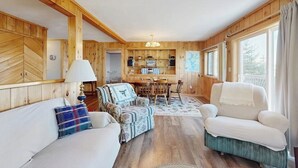 A wooden interior with a sofa, armchair, and dining table. - Lakefront Home With Private Dock, Mooring, Pebble Beach, Grill, & Firepit (Greenville)