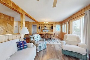 A wooden interior with a sofa, armchair, and dining table.