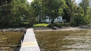 A wooden dock leading to a house surrounded by trees. - Lakefront Home With Private Dock, Mooring, Pebble Beach, Grill, & Firepit (Greenville)