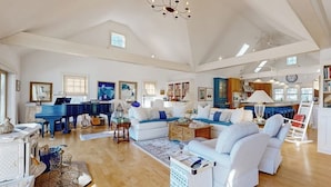 Uma sala de estar ampla com um piano, sofás e um candelabro.