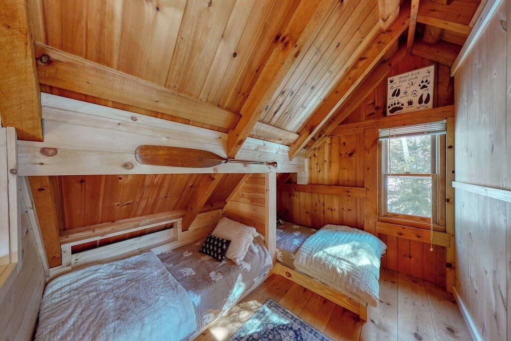 A wooden cabin with bunk beds, a window, and a wall-mounted sign.