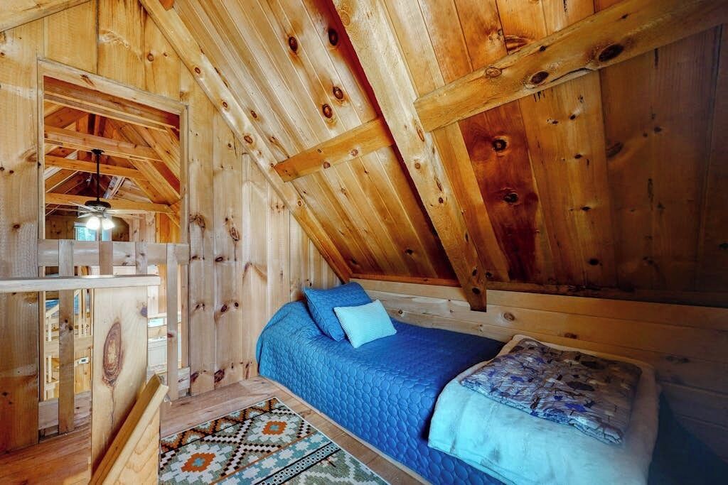 Een houten interieur met een bed, een rug met een patroon en een plafond met zichtbare balken.