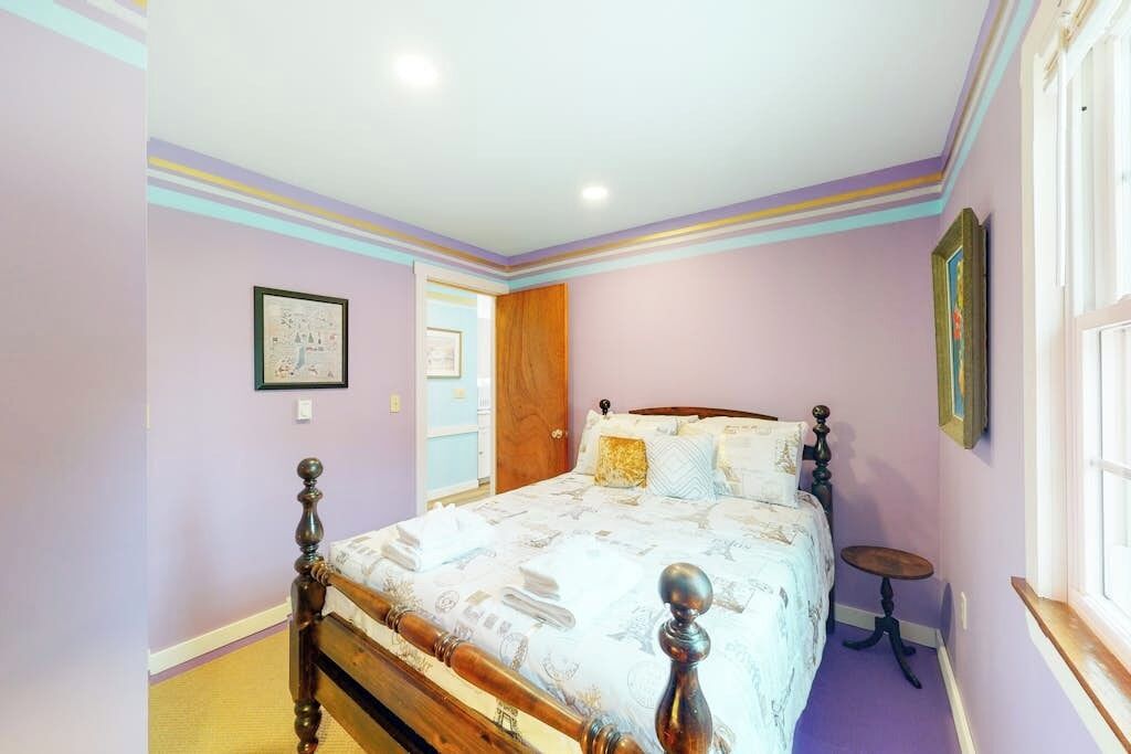 Un dormitorio con una cama de madera, una mesita redonda y una ventana.