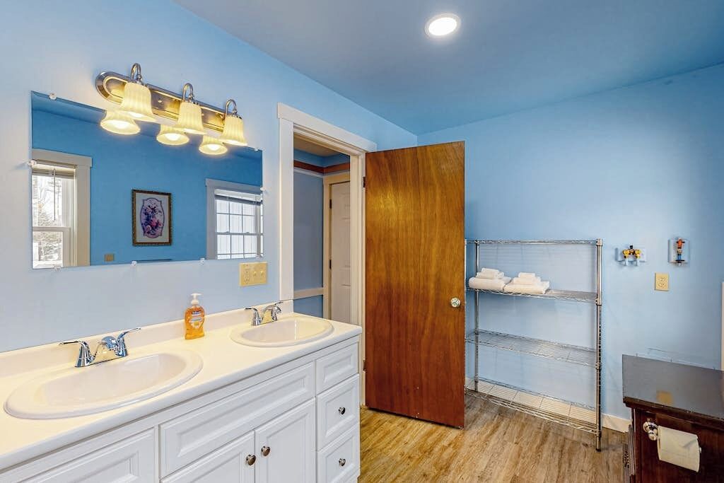 A bathroom with two sinks, a mirror, and a wooden door.
