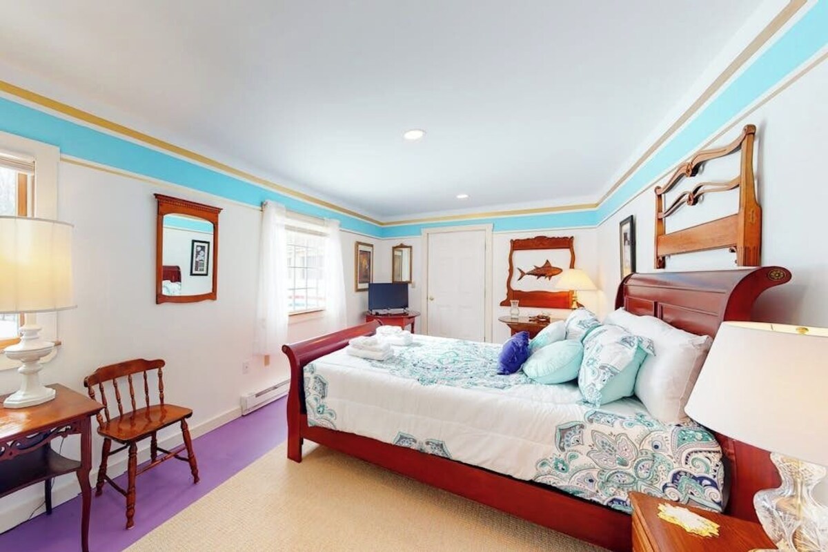 A bedroom with a bed, a chair, a desk, and a television.
