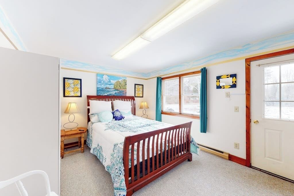 A bedroom with a bed, bedside tables, a window, and a door.