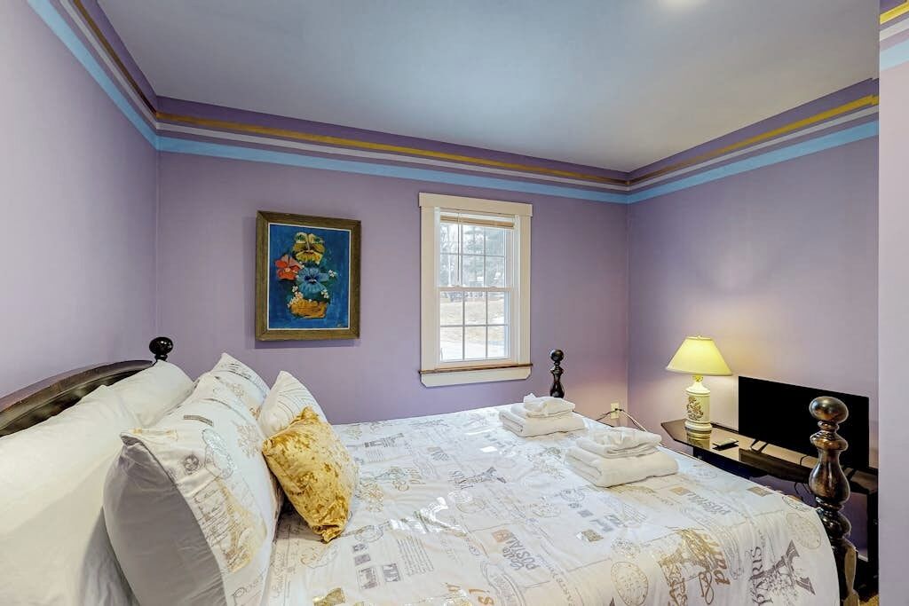 Une chambre à coucher avec un lit, une fenêtre, un tableau et une lampe.