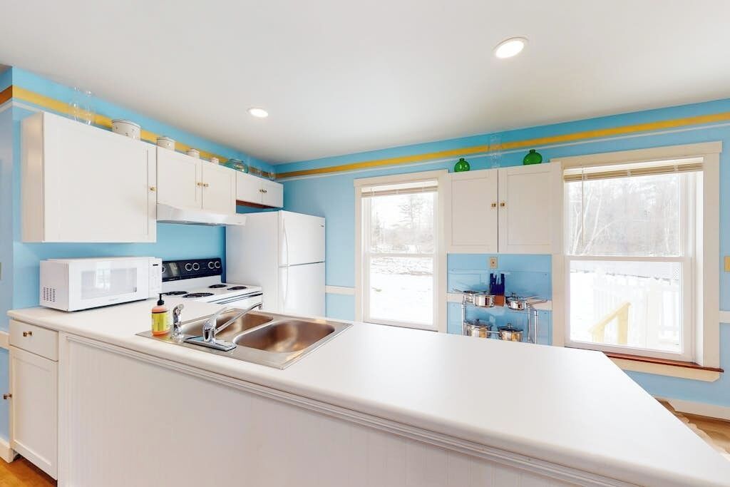 A kitchen with white cabinets, a microwave, a stove, and a sink.
