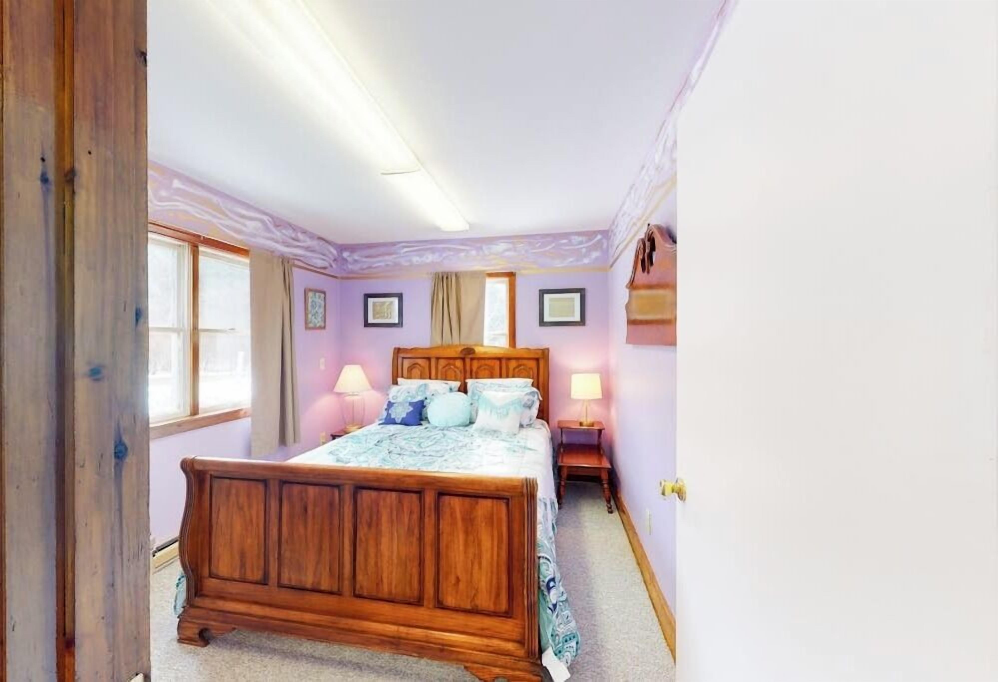 Un dormitorio con una cama de madera, dos lámparas de noche, una ventana y una puerta.