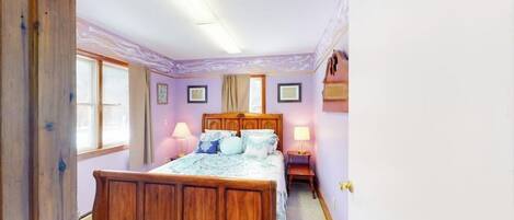 Un dormitorio con una cama de madera, dos lámparas de noche, una ventana y una puerta.