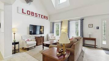 A living room with a TV, a sofa, a chair, a coffee table, and a sign that reads 'LOBSTERS'.