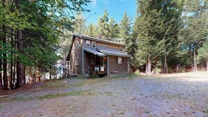 Ein rustikales Blockhaus mit Veranda, umgeben von dichtem Wald.