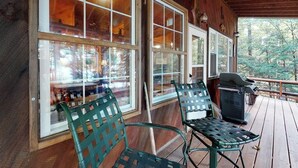 Eine Holterrasse mit großen Fenstern, Sitzmöglichkeiten im Freien und einem Grill.