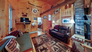 Ein Blockhaus-Interieur mit Sofa, Ledersessel und Kamin.
