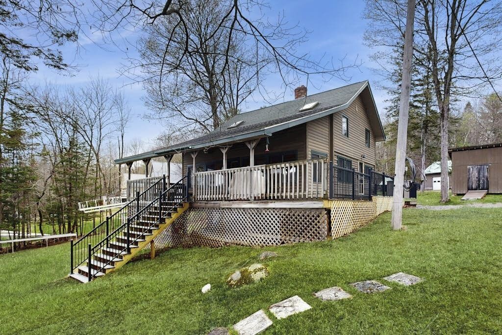 Une cabane en bois avec une véranda, un escalier et une cour clôturée.