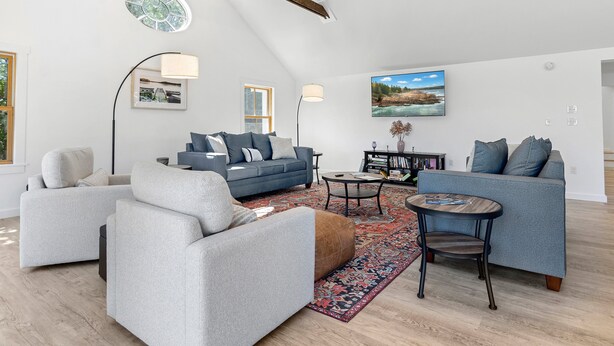 A spacious living room with a high ceiling, a large window, and a modern fireplace. - Gorgeous Oceanfront Home With Hot Tub, Modern Remodel, and Stunning Views (Wiscasset)
