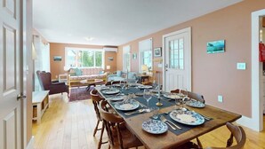 A dining area with a long table set for six, surrounded by chairs. - Charming Cape-style House With Panoramic River Views and Modern Amenities (Bath)