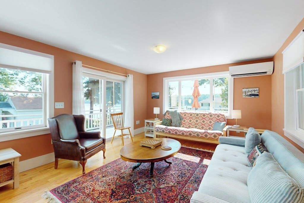 Un salon comprenant un canapé, un fauteuil, une table basse et un tapis à motifs.