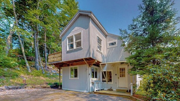 Ein zweistöckiges Haus mit Veranda, Garage und Auffahrt.
