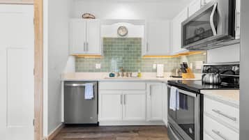 A modern kitchen with white cabinetry, a stainless steel dishwasher, a microwave, and a built-in oven.