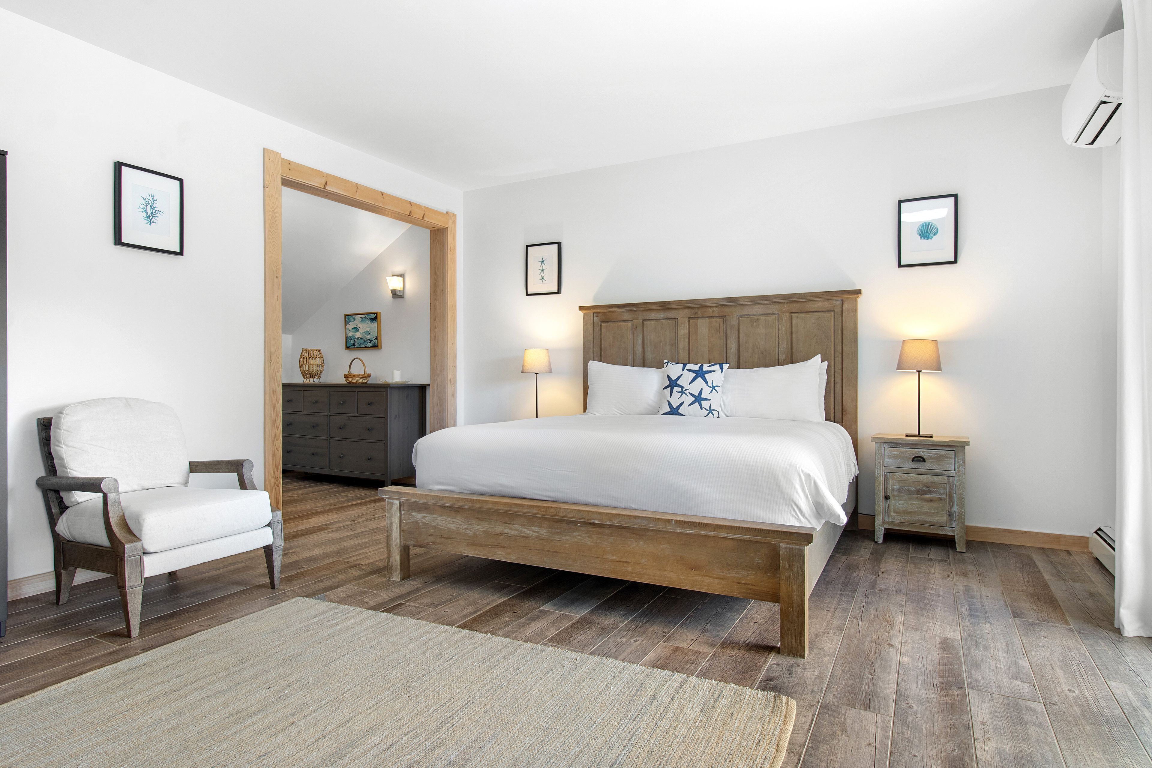 Un dormitorio con una cama de madera, una silla, un tocador y un espejo.