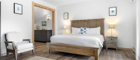 Un dormitorio con una cama de madera, una silla, un tocador y un espejo.