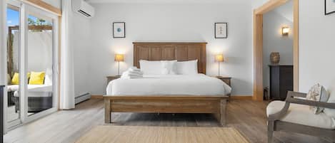 Une chambre à coucher avec un lit en bois, deux lampes de chevet, une grande fenêtre donnant sur un beau paysage et un plancher en bois.