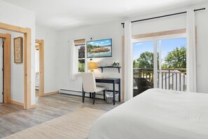 Une chambre à coucher comprenant un lit, un bureau avec une chaise, un téléviseur et une fenêtre donnant sur l’extérieur.