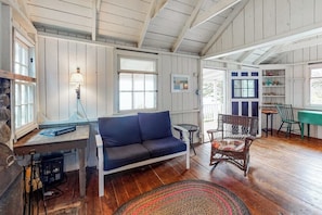 A cozy room with a blue sofa, a wicker chair, a small table, and a lamp. - Dog-friendly Oceanfront Cottage With Views (Port Clyde)