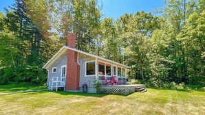 A small house with a porch, a chimney, and a lawn. - Classic Home Overlooking the St. George River With Deck & Great Views (Tenants Harbor)