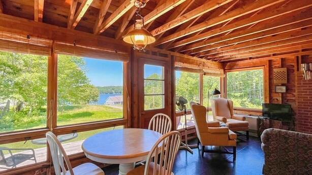 A wooden interior with large windows, a round table, and chairs. - Classic Home Overlooking the St. George River With Deck & Great Views (Tenants Harbor)
