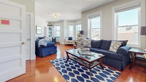 A spacious living room with a blue sofa, a coffee table, and a patterned rug. - Admiral's Quarters (Boothbay Harbor)