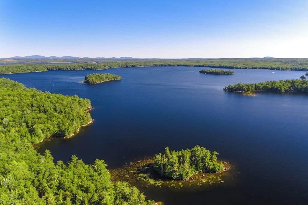 A large body of water with several small islands surrounded by dense forest.